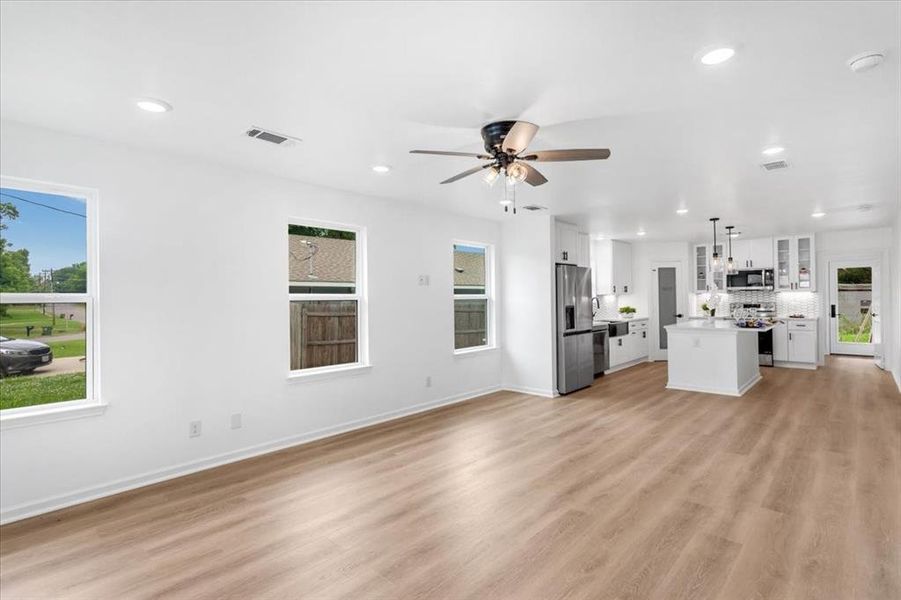 Unfurnished living room with ceiling fan and light wood flooring