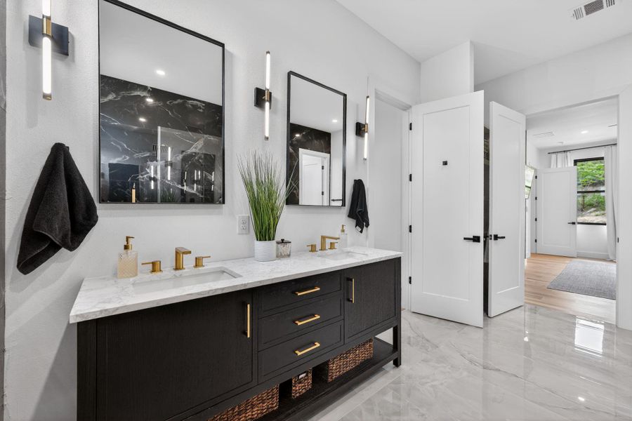Full bathroom featuring double vanity and light marble finish floors