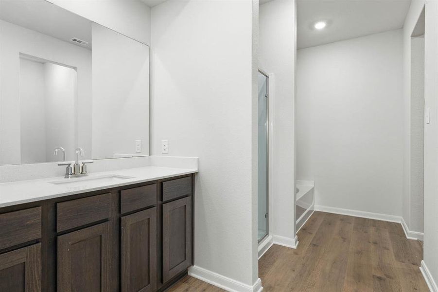 Full bathroom featuring dark wood-type flooring, vanity, a stall shower, and a bath Full bathroom featuring dark wood-type flooring, vanity, a stall shower, and a bath