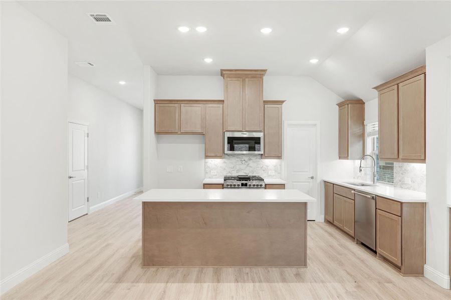 Kitchen with light wood cabinets, center island, stainless steel appliances, and light hardwood floors Kitchen with light wood cabinets, center island, stainless steel appliances, and light hardwood floors