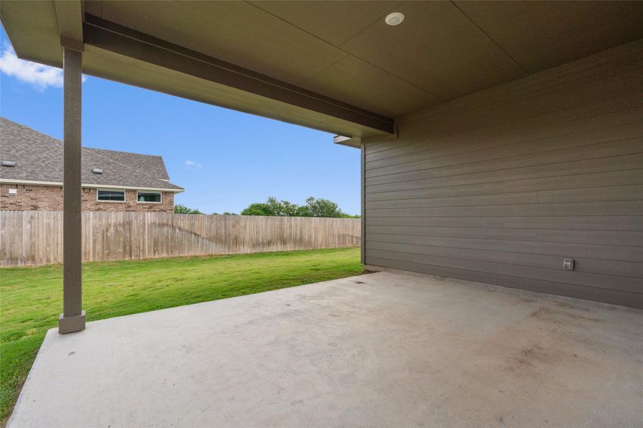 A spacious covered patio invites relaxation and outdoor enjoyment, overlooking a verdant fenced yard.