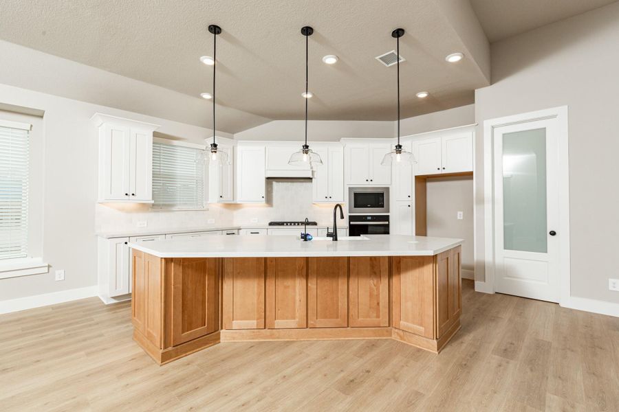 The stunning and generously sized center island features a breakfast bar, perfect for casual dining and entertaining. The island is beautifully designed with pristine quartz countertop and elegant pendant lights. The walk-in pantry, with decorative door, is sure to fit all your space needs.