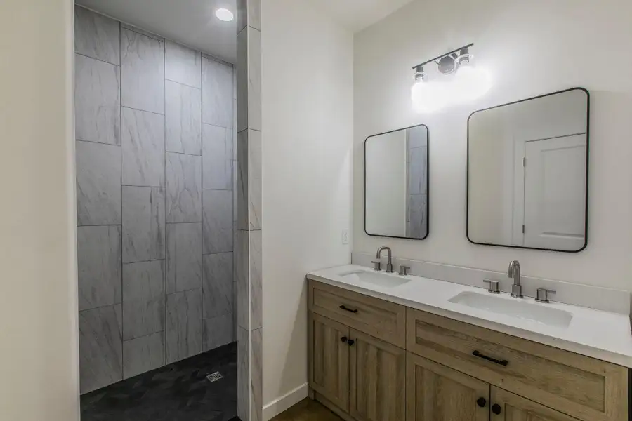 Bathroom featuring double vanity and a tile shower