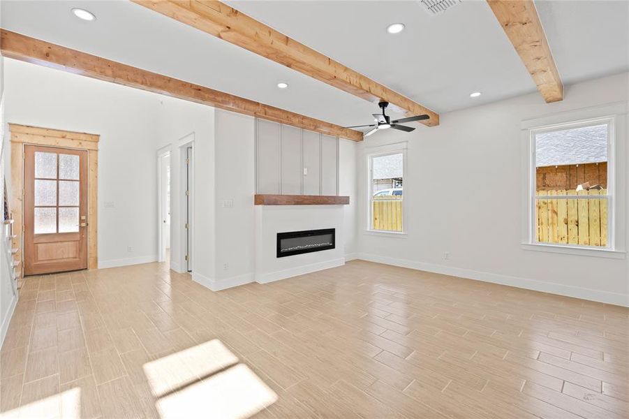 Unfurnished living room featuring recessed lighting, beam ceiling, healthy amount of natural light, wood tiled floors, and a fireplace Unfurnished living room featuring recessed lighting, beam ceiling, healthy amount of natural light, wood tiled floors, and a fireplace