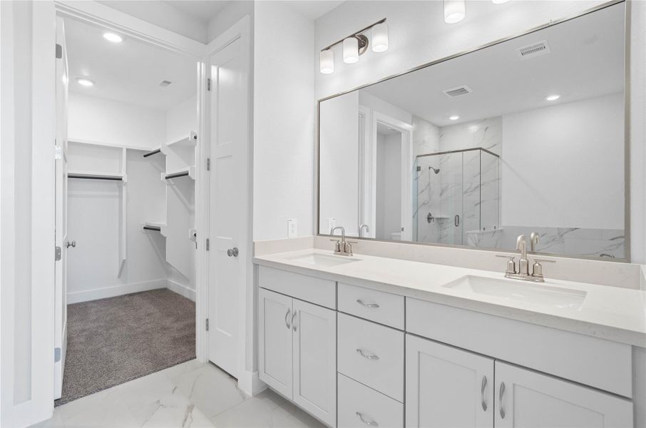 Retreat to a private, spa-like primary bathroom designed for relaxation and convenience. A generous double vanity with modern cabinetry offers ample space for two people. The connecting walk-in closet makes getting ready convenient. Retreat to a private, spa-like primary bathroom designed for relaxation and convenience. A generous double vanity with modern cabinetry offers ample space for two people. The connecting walk-in closet makes getting ready convenient.
