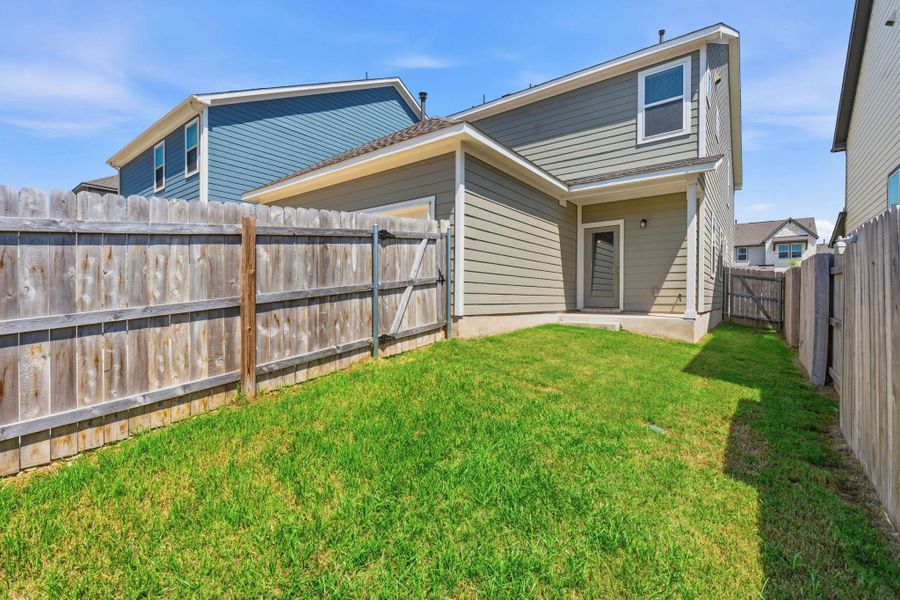 A well-maintained lawn stretches to the privacy fencing enclosing a modern home's exterior. A well-maintained lawn stretches to the privacy fencing enclosing a modern home's exterior.