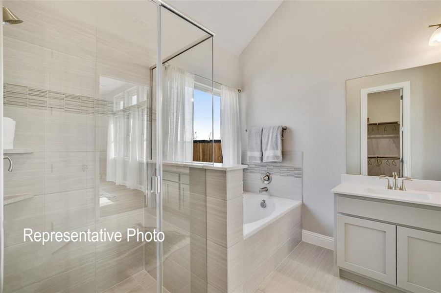 Bathroom featuring shower with separate bathtub, tile patterned flooring, vanity, and lofted ceiling