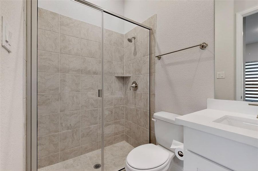 Bathroom featuring a textured wall, a stall shower, and vanity
