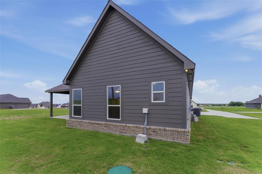 Exterior featuring dark gray siding, a pitched roofline, and a brick skirt foundation