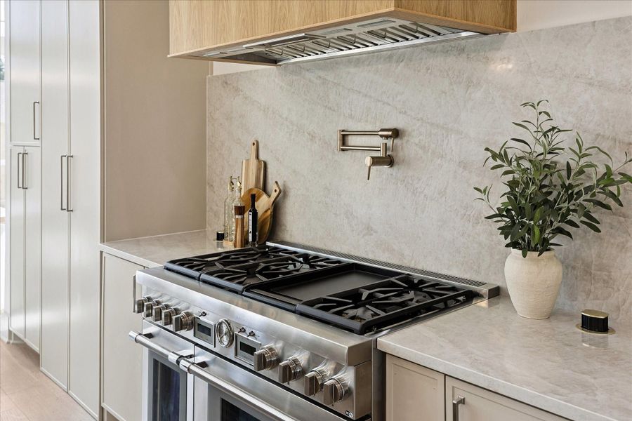 Home chefs will appreciate the Thermador 48-inch range, custom vent hood and convenient pot filler, while the full slab Taj Mahal quartzite backsplash with under-cabinet lighting keeps the look polished and beautifully cohesive.