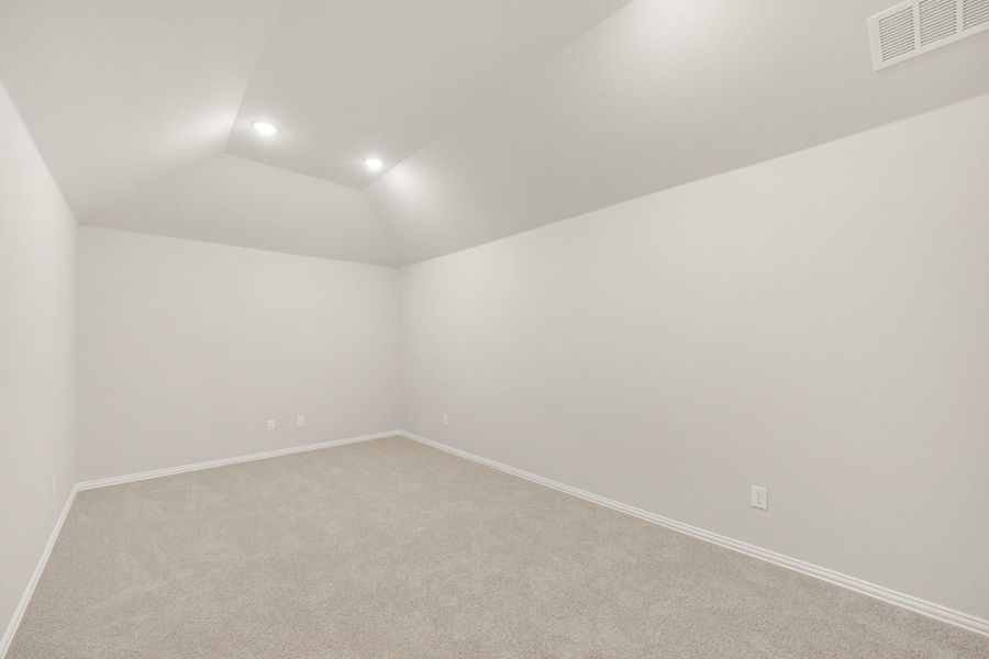 Empty bedroom with vaulted ceiling, recessed lighting, and beige carpet
