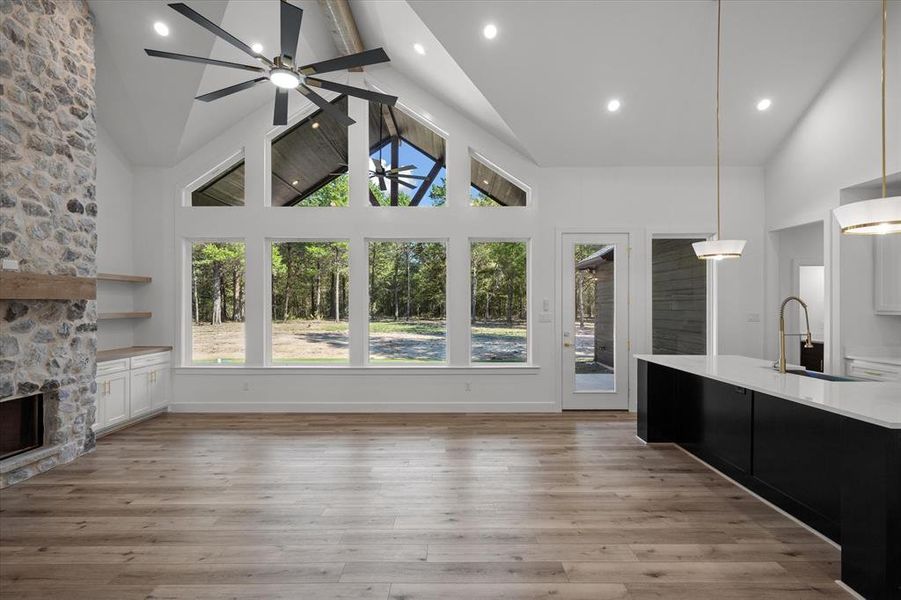 Open concept living area with ample windows to soak in natural light and views along with a cozy stone fireplace