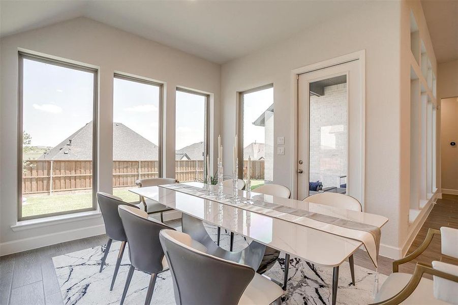 Dining area with light wood-style floors, baseboards, and lofted ceiling Dining area with light wood-style floors, baseboards, and lofted ceiling