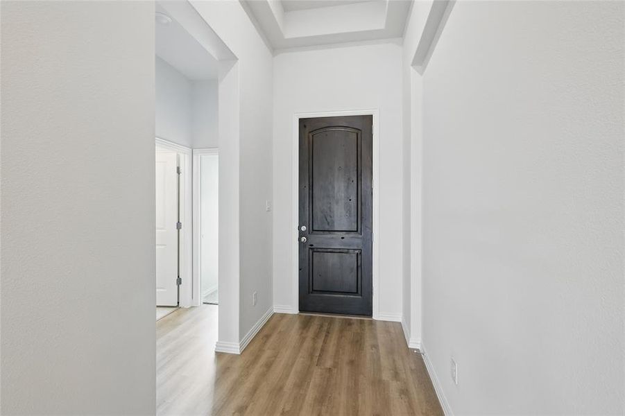 Hall featuring light wood-style floors and a towering ceiling