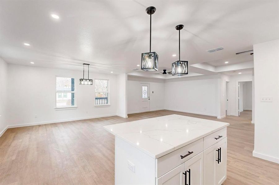 Kitchen with white cabinets, a center island, light hardwood / wood-style floors, and hanging light fixtures