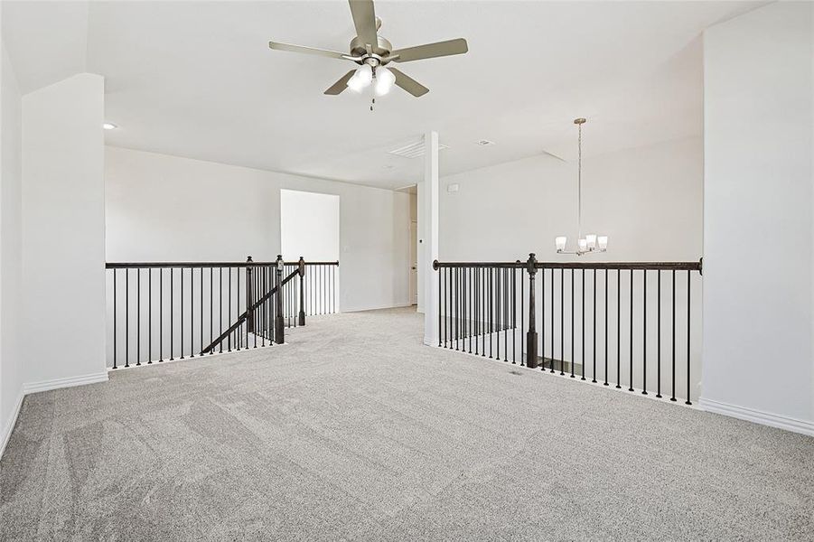 Carpeted empty room with a ceiling fan and suspended lighting