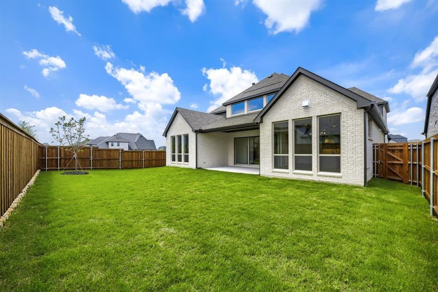 Expansive backyard featuring a manicured lawn, a young tree, and a full privacy fence Expansive backyard featuring a manicured lawn, a young tree, and a full privacy fence