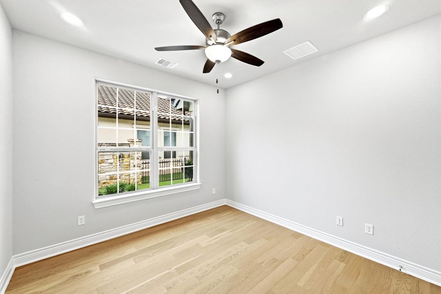 Bright interior space featuring a window with grid panes, wood-finish flooring, recessed lighting, a ceiling fan, and white baseboards