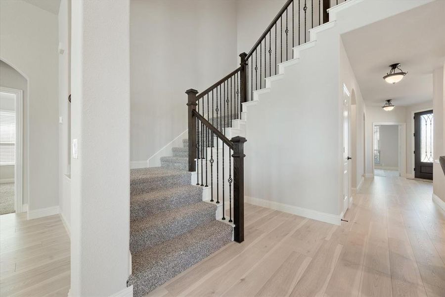 Stairway with iron balusters leads to game and media rooms and secondary bedrooms.