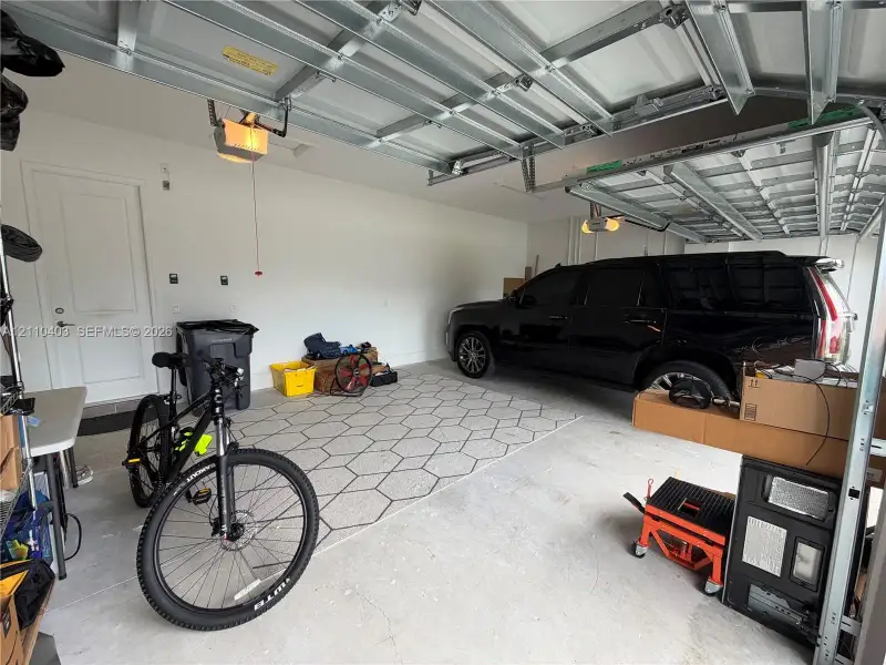 Two-car garage featuring a concrete floor, automated overhead door, and a solid-core interior access door