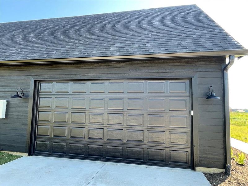 Dark gray paneled garage door with a concrete driveway