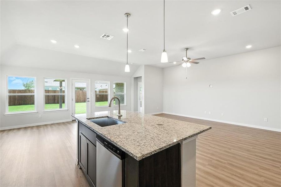 Kitchen with open floor plan, light wood-style flooring, stainless steel dishwasher, pendant lighting, and recessed lighting