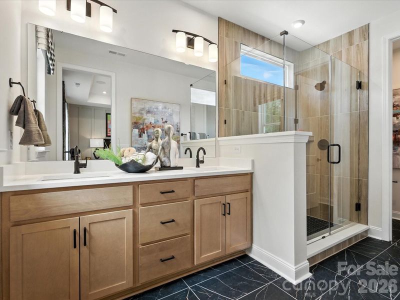 Dual vanity primary bathroom with warm brown cabinets Dual vanity primary bathroom with warm brown cabinets
