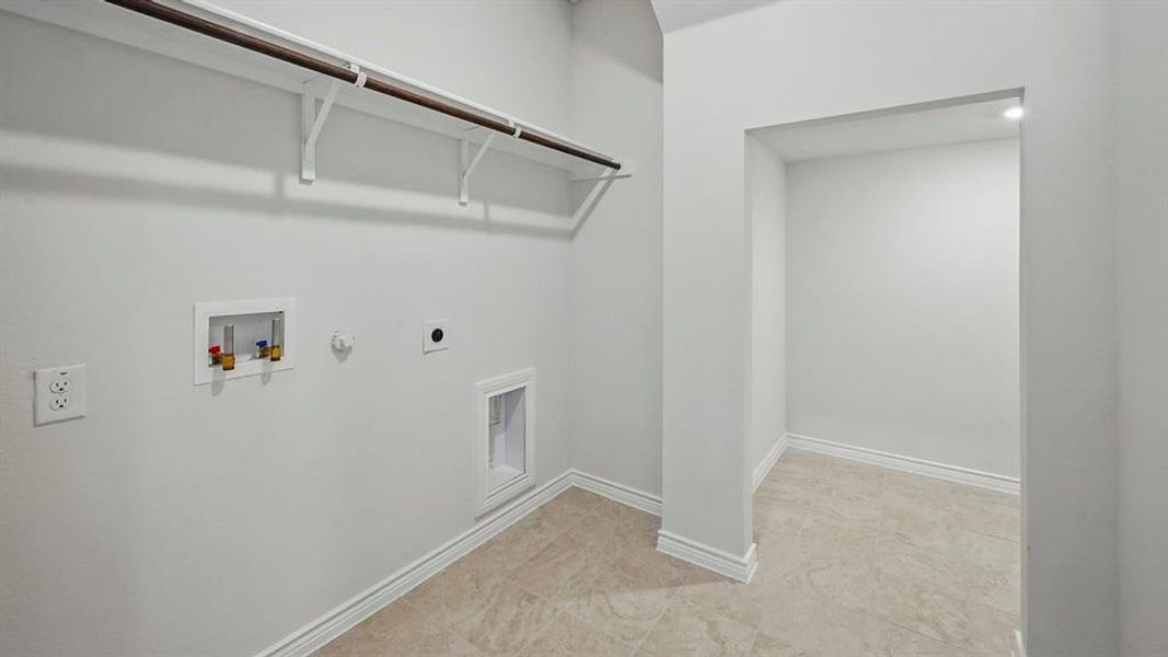 Utility area featuring light-toned flooring, white baseboards, and a clothing rod with shelving Utility area featuring light-toned flooring, white baseboards, and a clothing rod with shelving