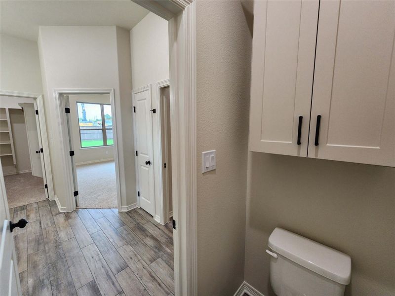 Hallway featuring wood-finish flooring, multiple white paneled doors with black hardware, and a built-in storage cabinet
