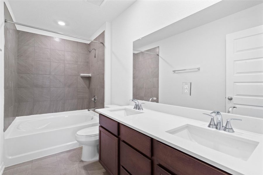 This primary bathroom is definitely move-in ready! Featuring stained cabinets with light countertops, dual vanities, tub/shower combination with tile surround, all with sleek and modern finishes.