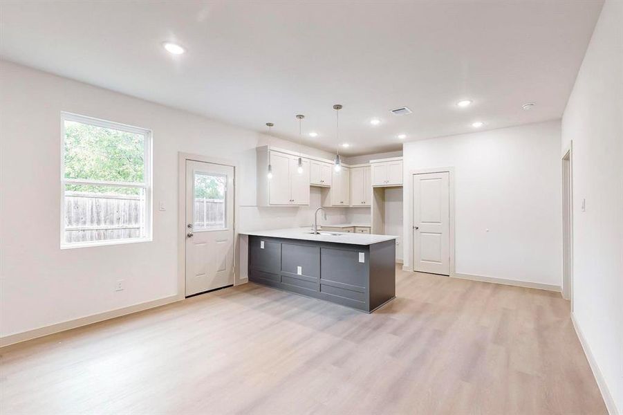 Kitchen with decorative light fixtures, light countertops, white cabinetry, a sink, and a peninsula