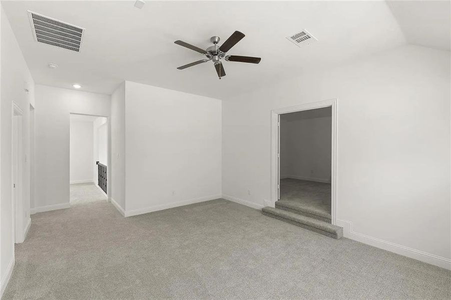 Carpeted spare room with ceiling fan and lofted ceiling