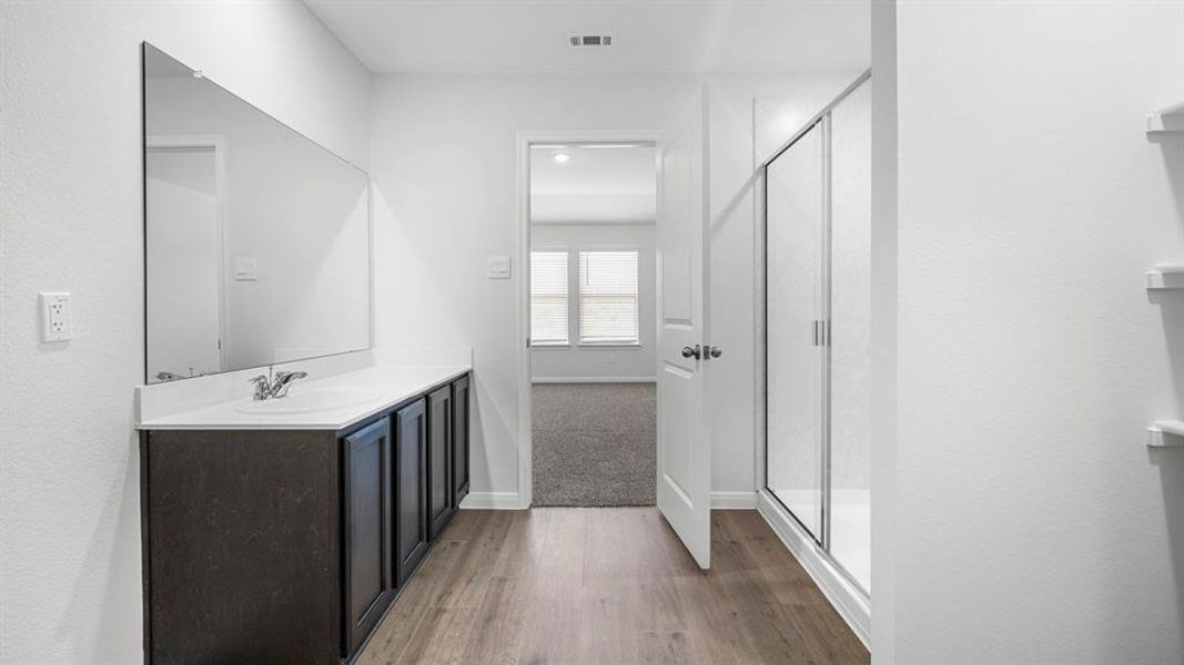 Full bathroom with vanity, a stall shower, and dark wood finished floors