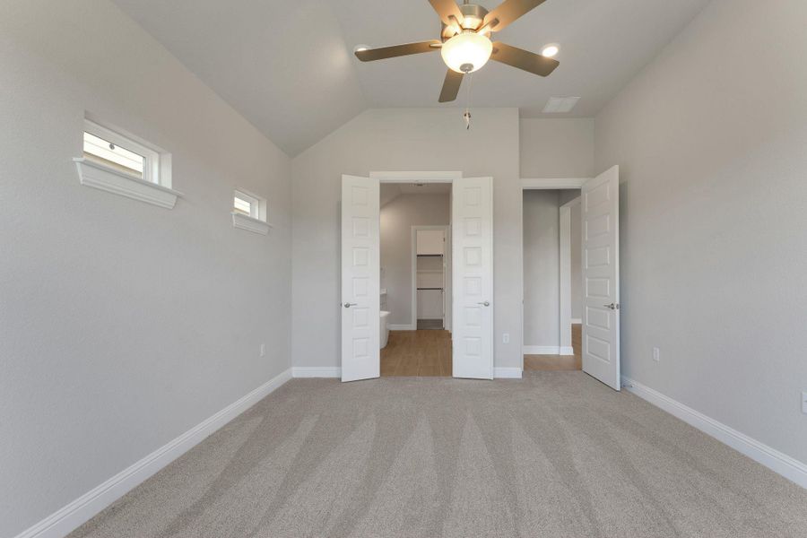 Unfurnished bedroom with light carpet, lofted ceiling, and ceiling fan Unfurnished bedroom with light carpet, lofted ceiling, and ceiling fan