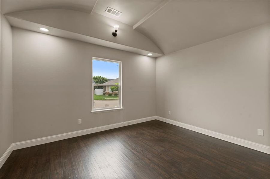 Spare room featuring baseboards, lofted ceiling, dark wood-style flooring, and recessed lighting