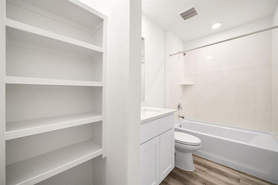 Secondary bathroom features light countertops and cabinets, shower/tub combo with tile surround, large mirror, sleek fixtures and modern finishes, plenty of space to accommodate any visiting family or guests.