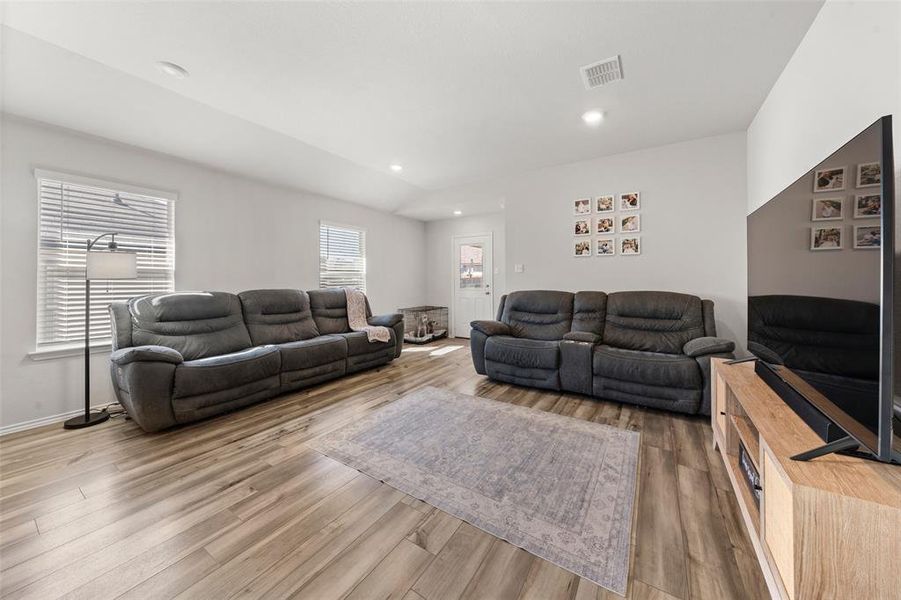 Living room featuring wood finished floors, recessed lighting, and vaulted ceiling