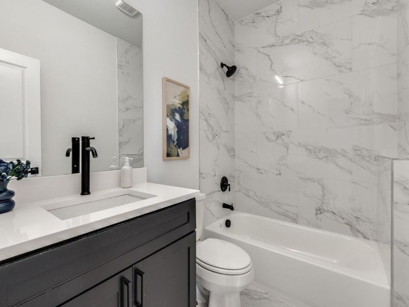 3rd Full bathroom featuring vanity, shower / tub combination, and marble look tiles.