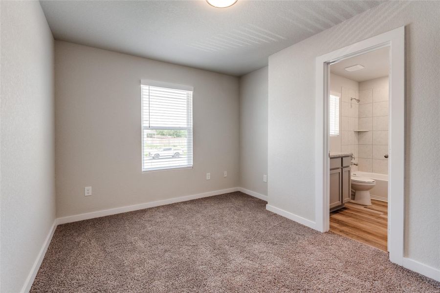 Unfurnished bedroom featuring light carpet and ensuite bathroom Unfurnished bedroom featuring light carpet and ensuite bathroom