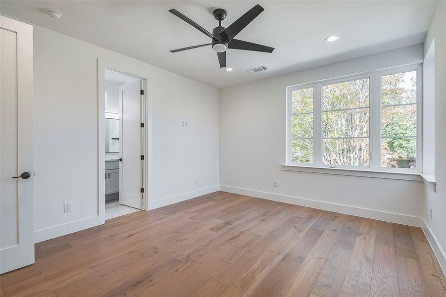 Unfurnished bedroom with light hardwood / wood-style flooring, ensuite bath, and ceiling fan