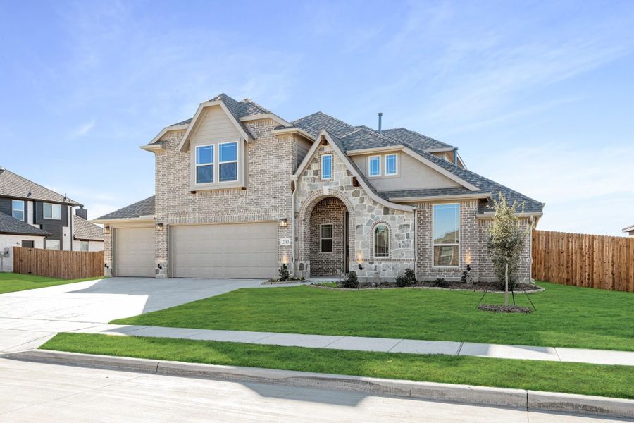 Two-story home with brick and stone exterior, two-car garage, arched entry, and green front lawn