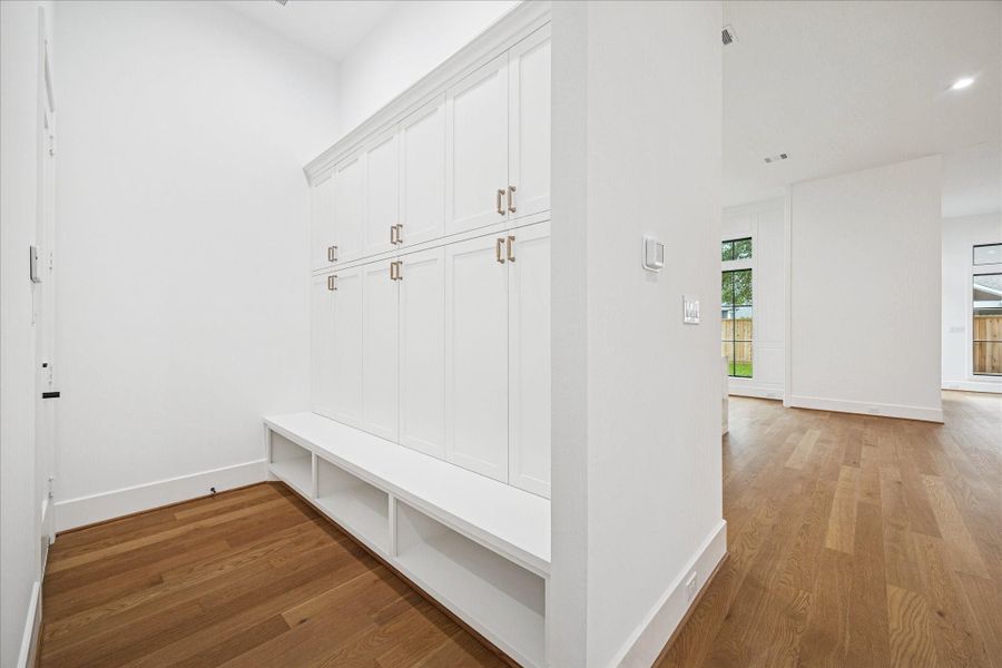 Custom cabinetry and concealed storage define a highly functional mudroom with integrated bench seating and durable marble surfaces. Positioned near the garage entry, this space supports organization and daily flow with ease. *Previous Project*