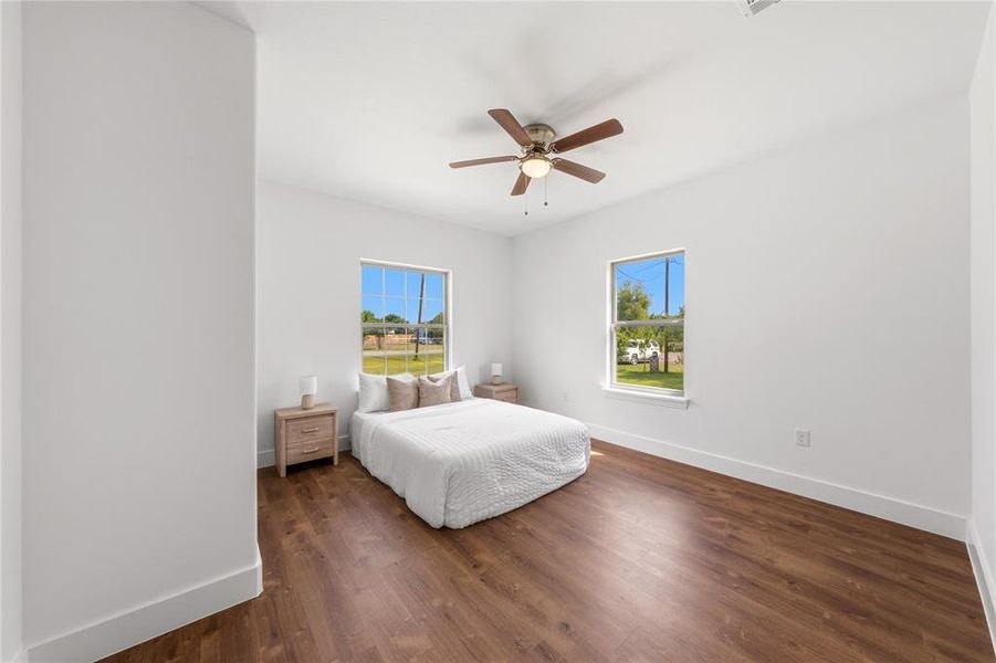 Spacious room featuring wood-finish flooring, white walls, and a ceiling fan with integrated lighting