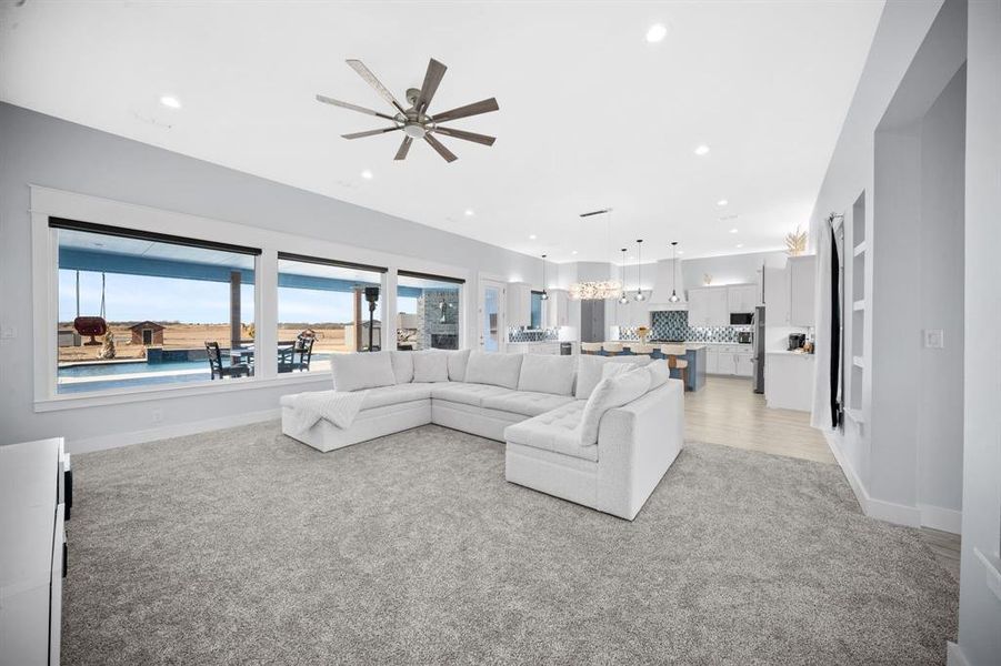Living area with light colored carpet, a ceiling fan, and recessed lighting