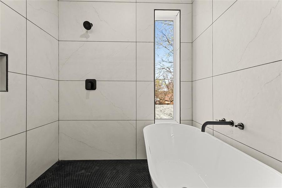 Bathroom featuring a soaking tub, tiled shower, and plenty of natural light