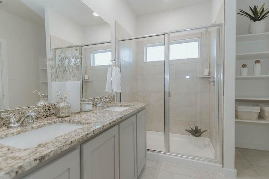 Bathroom with tile patterned flooring, a shower stall, and double vanity Bathroom with tile patterned flooring, a shower stall, and double vanity