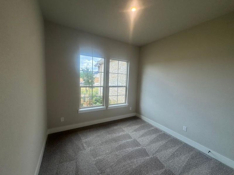 Interior room featuring a dual window system, neutral wall tones, patterned carpeting, and white baseboards