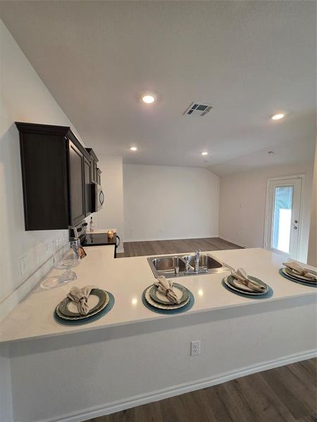 Kitchen with light countertops, dark wood-style floors, a peninsula, stove, and recessed lighting Kitchen with light countertops, dark wood-style floors, a peninsula, stove, and recessed lighting