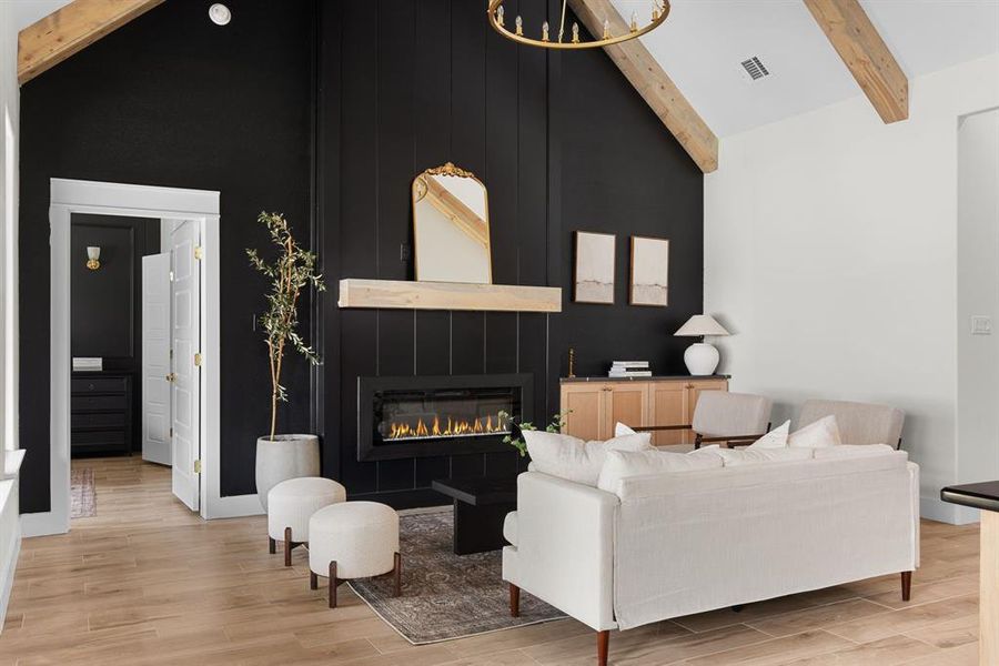 Living room featuring light wood-type flooring, high vaulted ceiling, a fireplace, and beamed ceiling