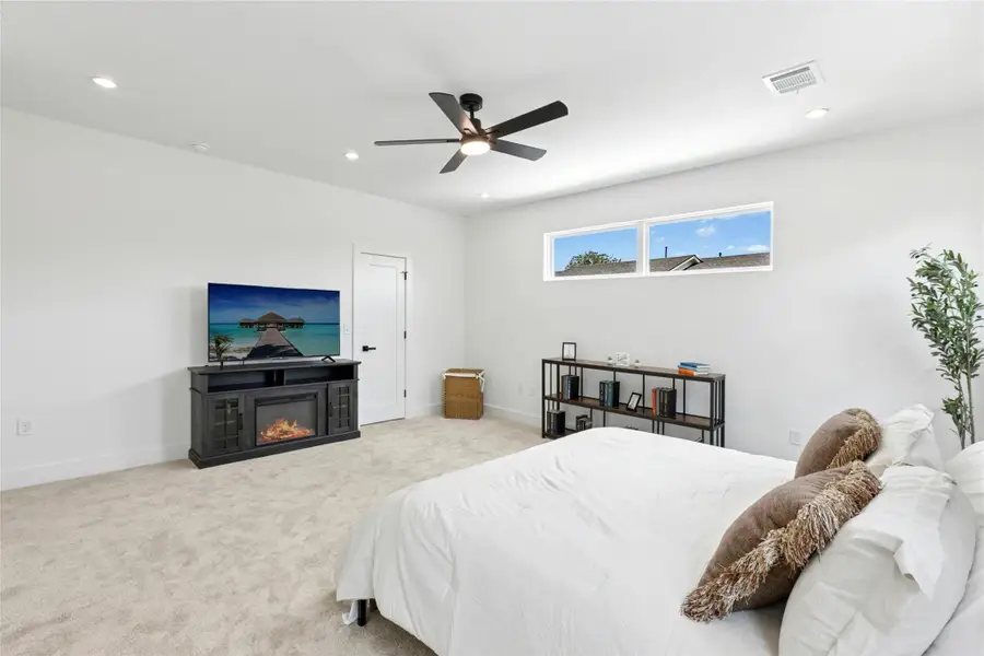 Carpeted bedroom with recessed lighting, a glass covered fireplace, and a ceiling fan